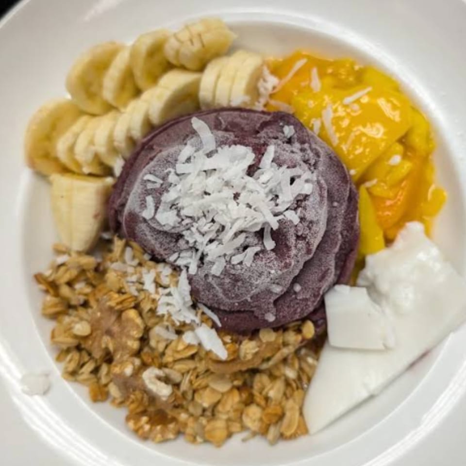 A Menehune Coffee Company acai bowl with bananas, mango, granola, coconut flakes, and coconut cream.